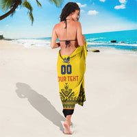 Yellow custom rugby sarong worn around hips, with crest icon, “YOUR TEXT,” and patterns