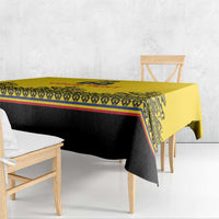 Yellow tablecloth corner close-up with black print, red/blue stripes, and woven motif trim.