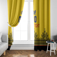 Yellow window curtain panel with blue crest and red text over black geometric trim