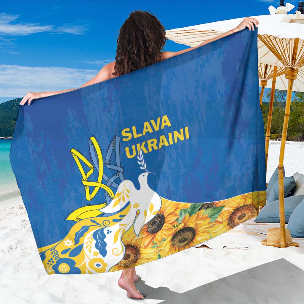 Blue Ukraine sarong with dove and sunflower graphic, held beachside