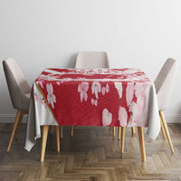 Red cherry blossom tablecloth with flying petals, draped over a square table