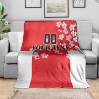Red and white custom blanket with Japanese waves and cherry blossoms, spread on couch