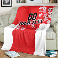 Red and white custom blanket with wave pattern and cherry blossoms, on striped sofa