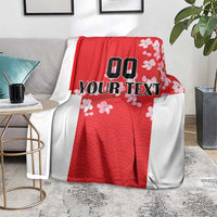 Red and white custom blanket with wave pattern and cherry blossoms, laid on rug
