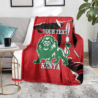 Red personalized blanket with green lion and Kenya print, shown folded on gray couch