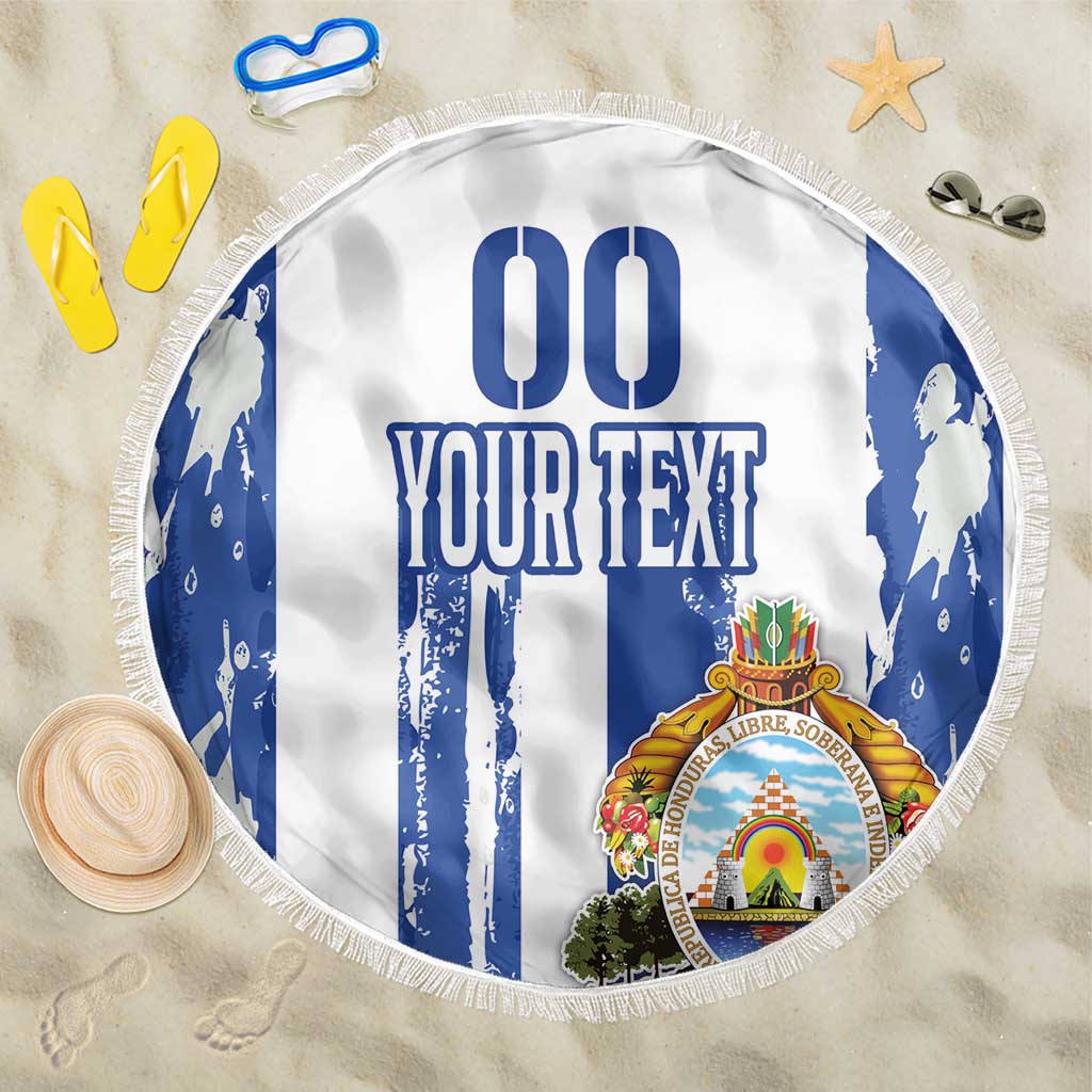 White round beach blanket with blue vertical stripes, crest graphic, and tassel fringe