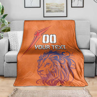 Orange football blanket draped over a sofa with lion and star plus “YOUR TEXT”