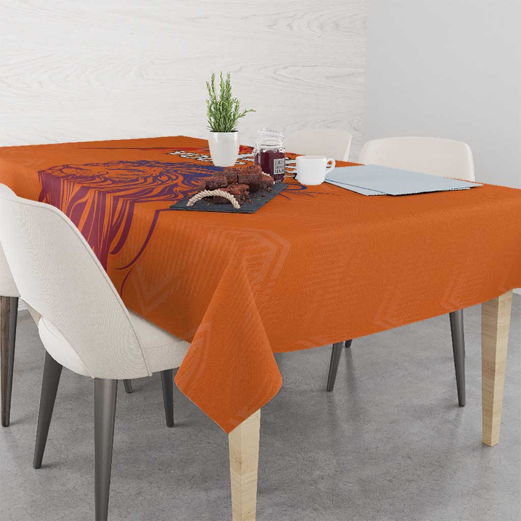 Orange printed tablecloth corner detail with lion graphic visible on the table