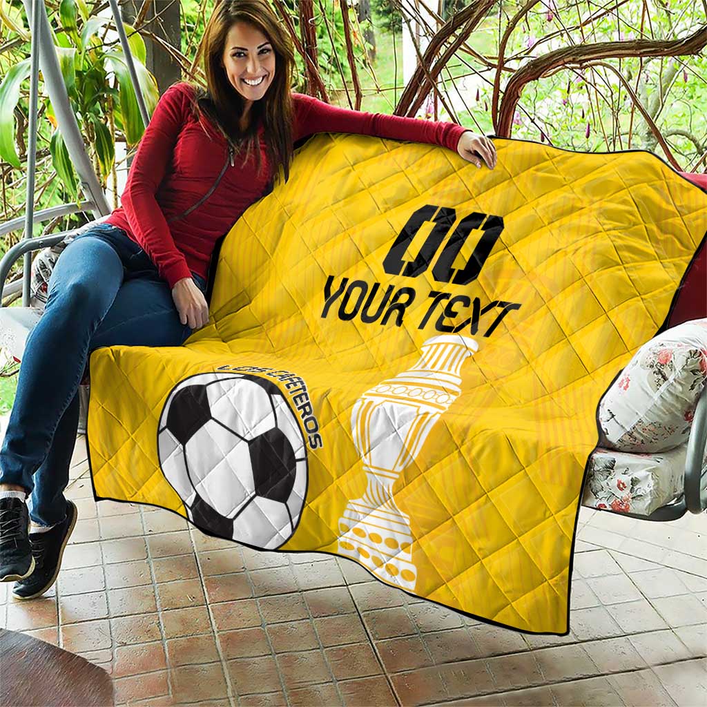 Yellow football quilt held up, diamond quilting, soccer ball and trophy artwork