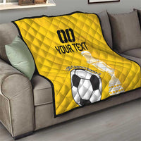 Yellow football quilt draped on sofa, diamond quilting, soccer ball and trophy print
