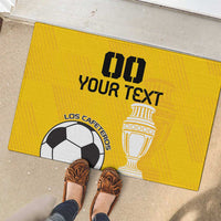 Yellow custom rubber football doormat with trophy and “Your Text” near shoes on tile floor.