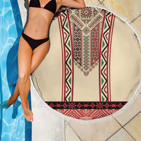 Round beige beach blanket with red geometric embroidery and white fringed edge