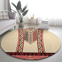 Beige round rug with central red embroidered motif and green triangle accents