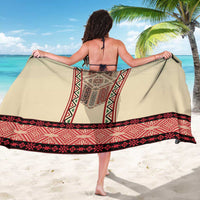 Beige sarong with red geometric embroidery border, worn with back showing