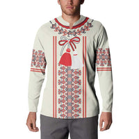 Beige long-sleeve sweatshirt on model with red, white, and blue folk panel and bell figure print
