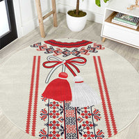 Beige round carpet with red, black, and white folk motif of a costumed girl