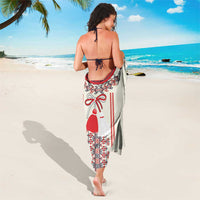 Beige sarong tied at waist, red and black embroidered dress-and-ornament folk pattern