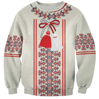 Beige crewneck sweatshirt with red, black, and white embroidered-style folk pattern and bow