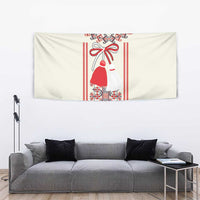 Beige wall tapestry with red folk dress figure and bow, surrounded by geometric motifs