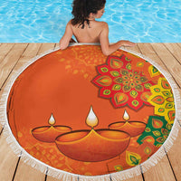 Round orange beach blanket with white fringe, mandala rangoli art and candle motif in center.