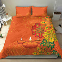 Orange bedding set with rangoli-style floral pattern, candle motif, and two matching pillows