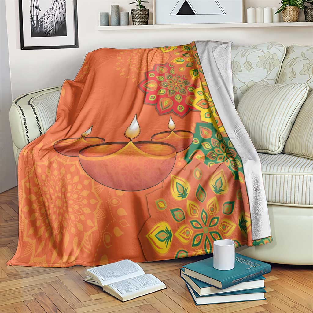 Saffron Diwali blanket on sofa with diya rangoli mandala pattern and leaf motifs