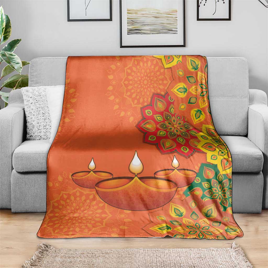 Saffron Diwali blanket on gray sofa with central diya lamp illustration and mandala border