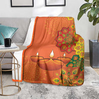Saffron Diwali blanket on couch arm with rangoli mandala and three diya lamps print
