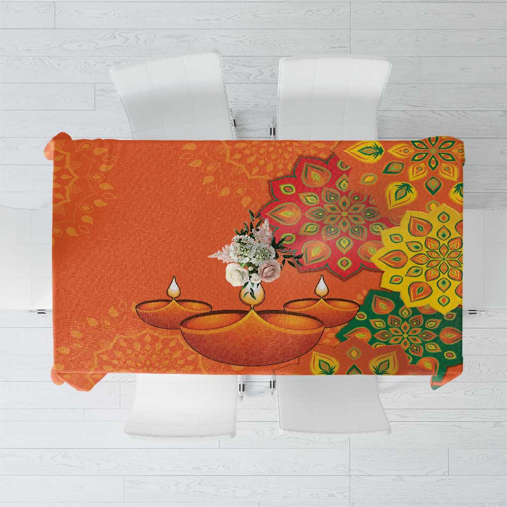 Saffron orange tablecloth with detailed green rangoli design on folded fabric