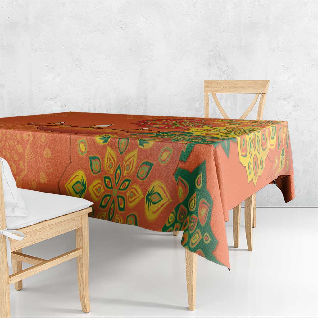Saffron orange tablecloth with green rangoli patterns draped over dining table