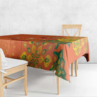 Saffron orange tablecloth with green rangoli patterns draped over dining table