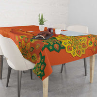 Saffron orange tablecloth with green rangoli motifs covering a tabletop