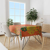 Saffron orange tablecloth with green rangoli-style patterns and scalloped border