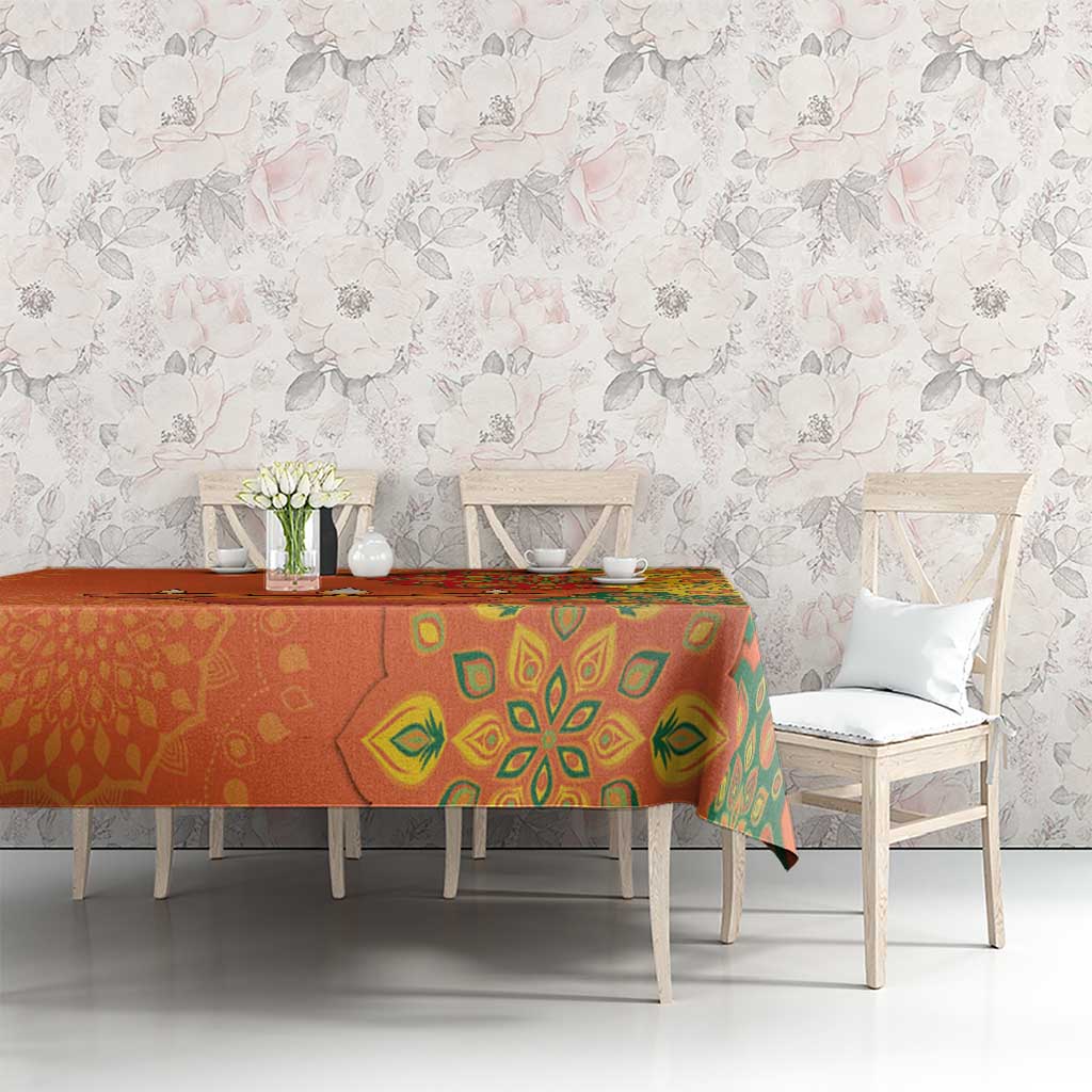 Saffron orange tablecloth with green rangoli pattern across dining table