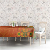 Saffron orange tablecloth with green rangoli pattern across dining table