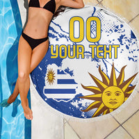 Round blue-and-white beach blanket showing “00 YOUR TEXT” and sun face, with fringe