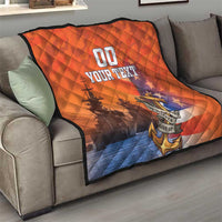 Orange and blue quilt on a sofa, diamond pattern with anchor emblem and “YOUR TEXT”