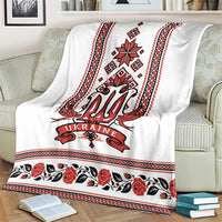White blanket featuring red trident emblem, folk stripes, and floral band along the bottom