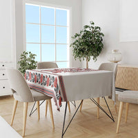 White tablecloth with red and black folk trident and border, draped over dining table