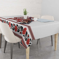White tablecloth with red and black folk floral print and patterned edge on table