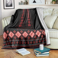 Folk pattern blanket: black with red geometric bands, draped on sofa