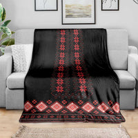 Black folk pattern blanket with red zigzag center and border, spread on couch