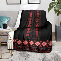 Black folk pattern blanket with red diamond motifs and zigzag border, on chair