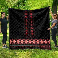 Black quilt laid flat outdoors with red vertical folk motif and red geometric border