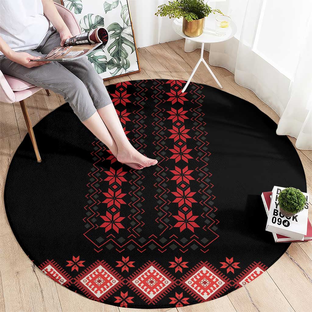 Round black carpet with red geometric folk pattern, zigzag and flower motifs