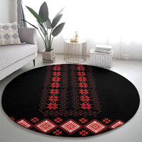 Round black carpet with red folk geometric motifs and symmetrical central medallion