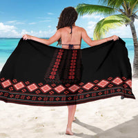 Black sarong with red vertical folk motif and patterned hem, worn as beach wrap
