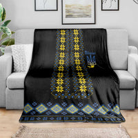 Black Ukraine folk blanket on sofa, blue and yellow geometric strip with trident emblem
