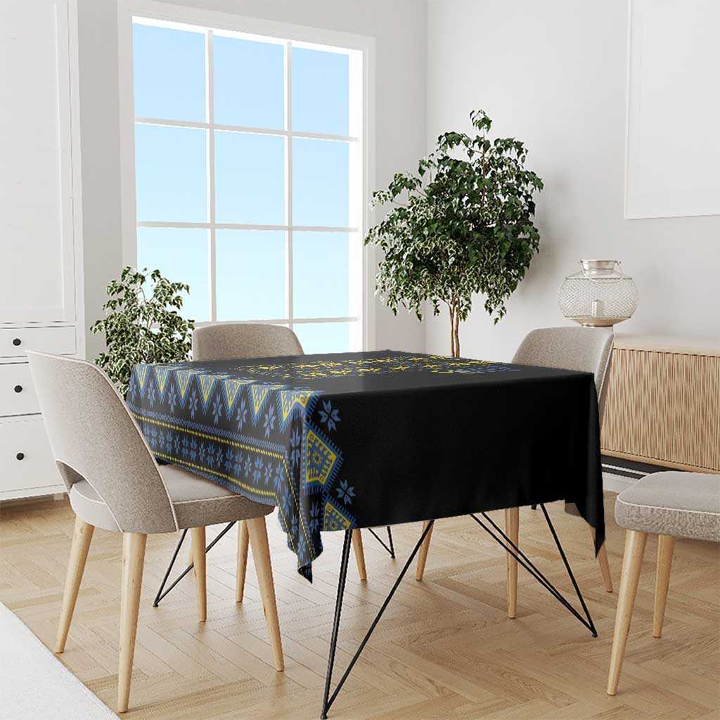 Square tablecloth draped over table; black fabric with blue and yellow folk border