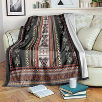 Black folk patterned blanket with red, white, and yellow geometric stripes and trim